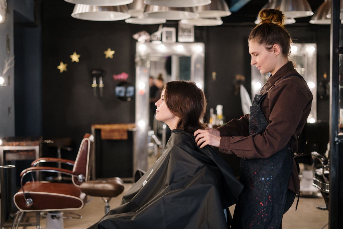 A hair stylist working with a client in a salon chair
